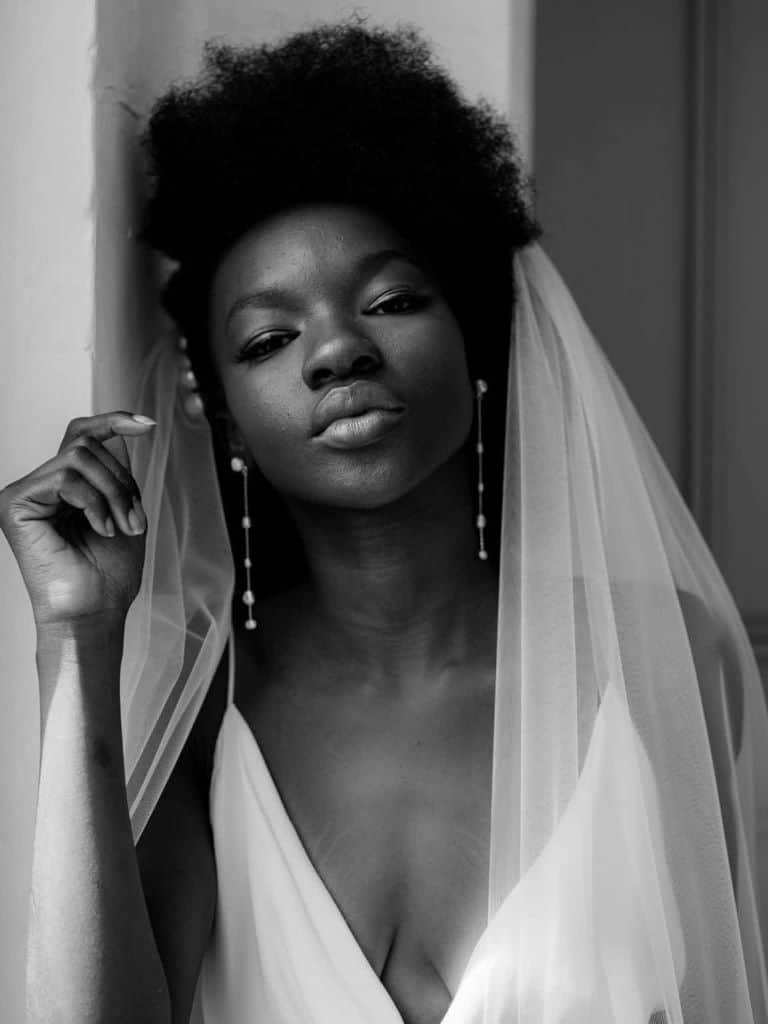 African bride with a styled afro and veil, wearing a minimal style to enhance her natural beautiful features in greyscale.