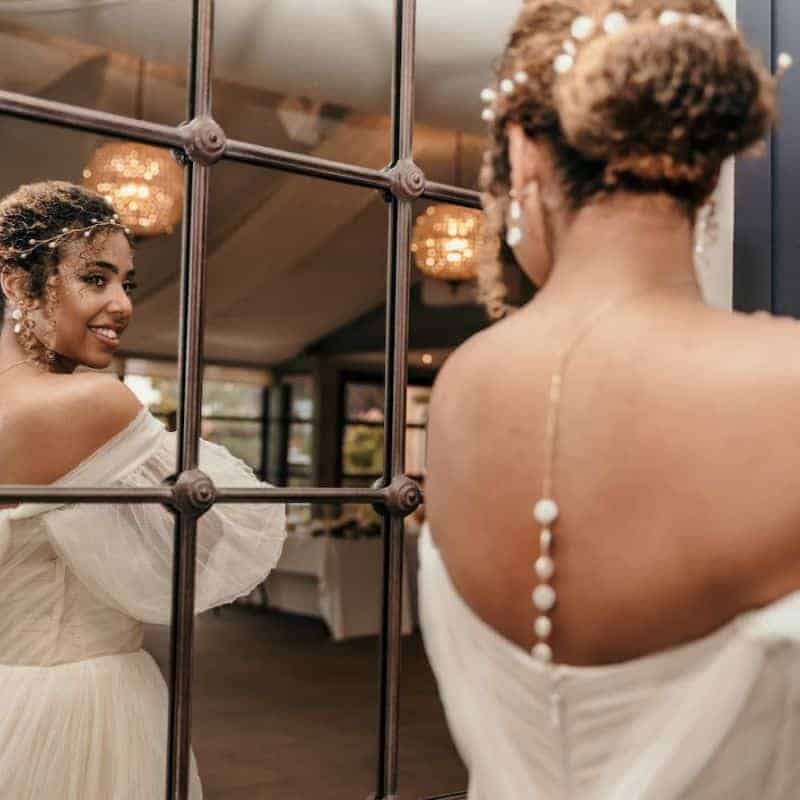 Mixed race bride wearing her curly hair in a bun updo with a pearl branch headband and hair wisps. Her natural look complements her ethereal style.